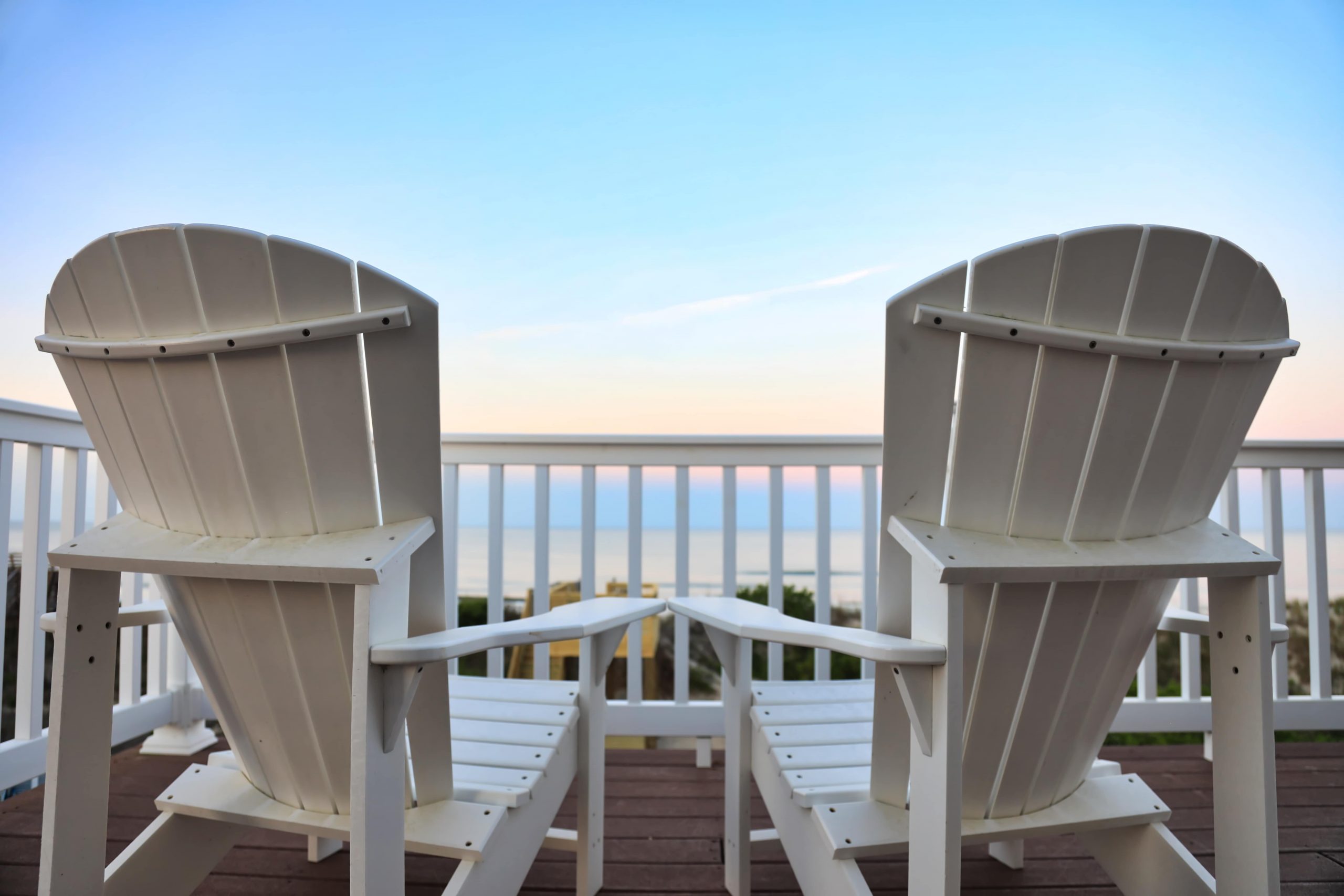 two beach chairs sitting on balony in front of ocean view