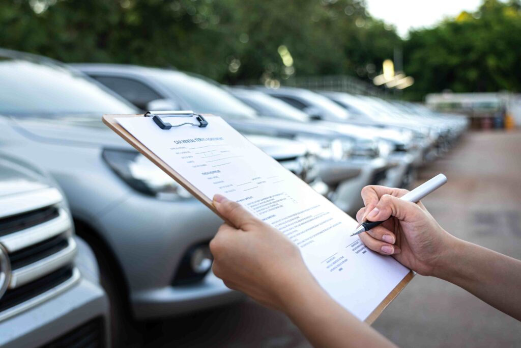 a person writing on a clipboard next to parked cars