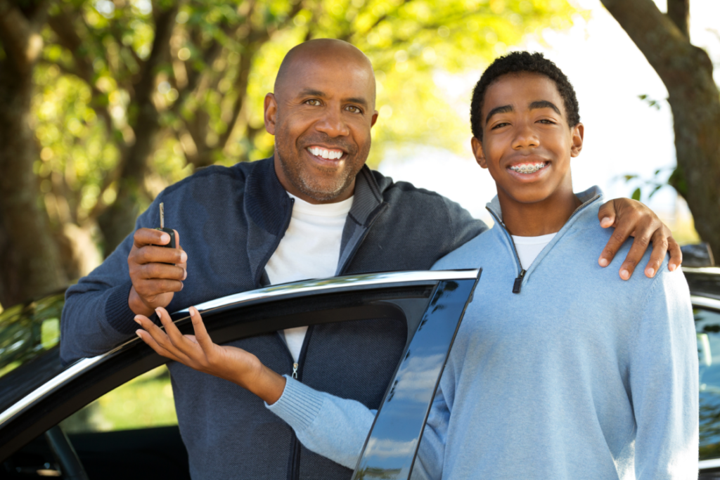 Young driver posing with his father and the car keys