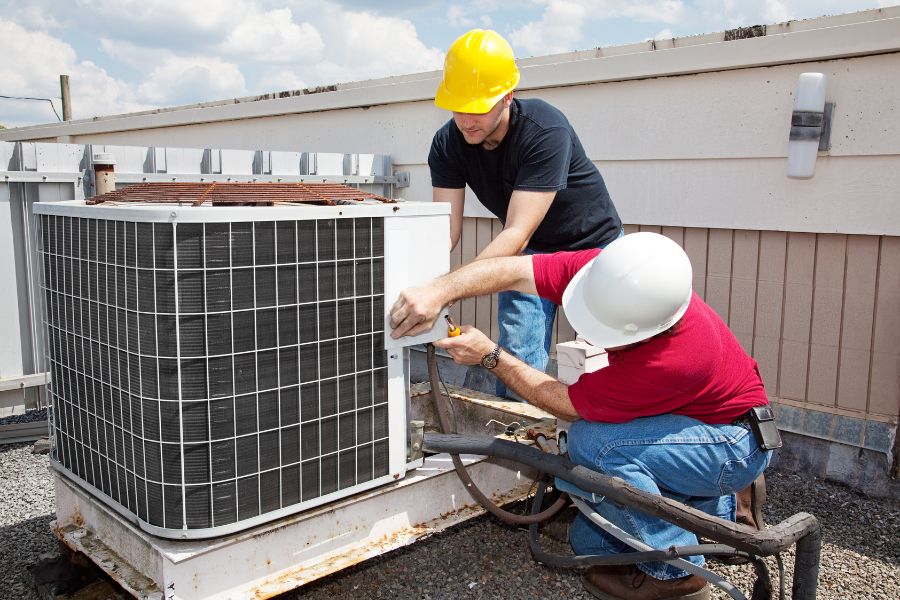 two men working on an air conditioner outside