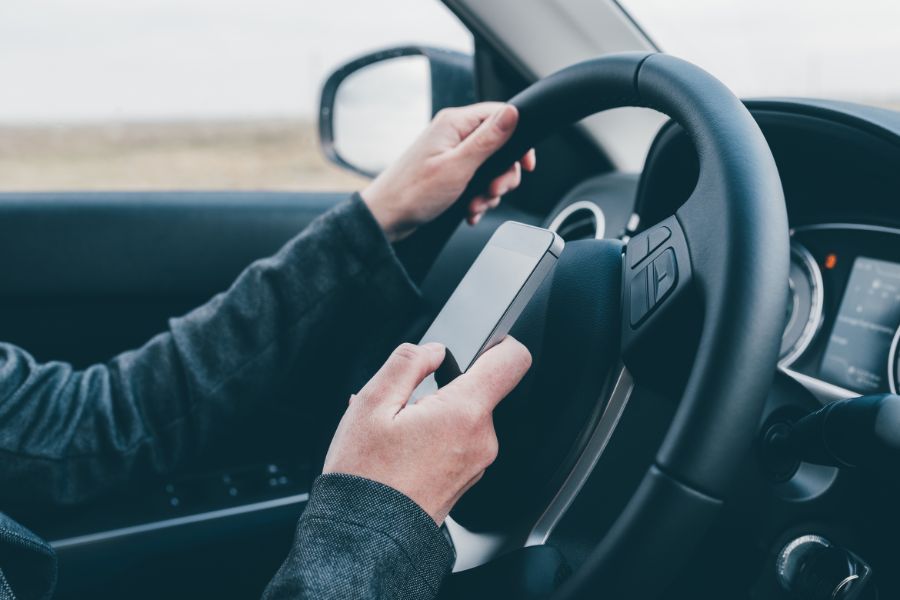 a person driving a car while holding a cell phone
