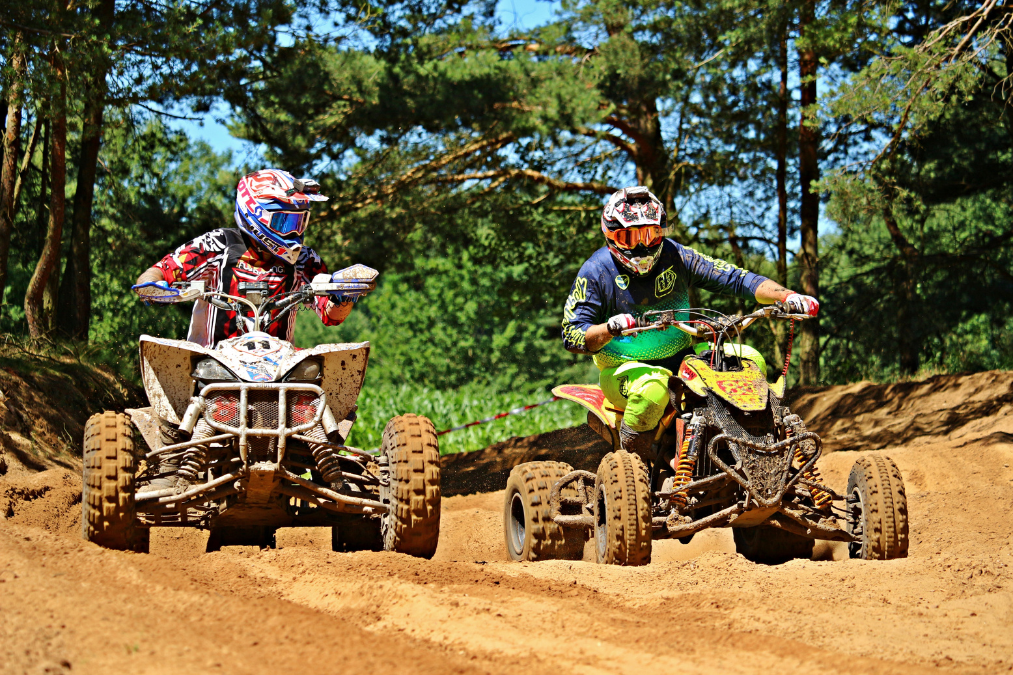 2 men riding ATVs side by side