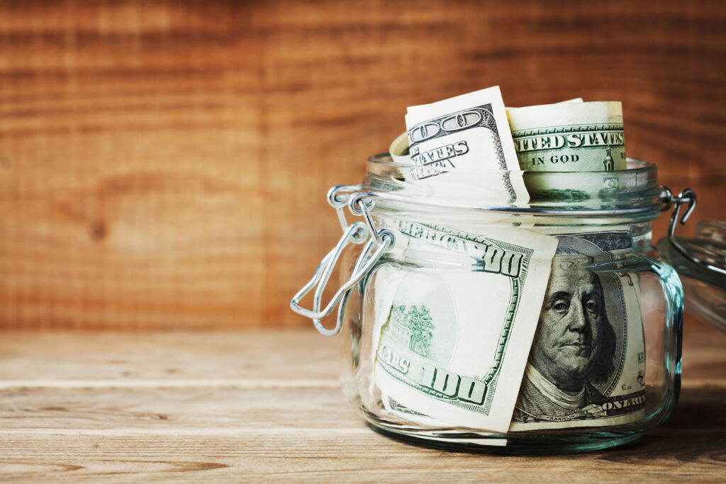 a glass jar filled with money sitting on wooden table