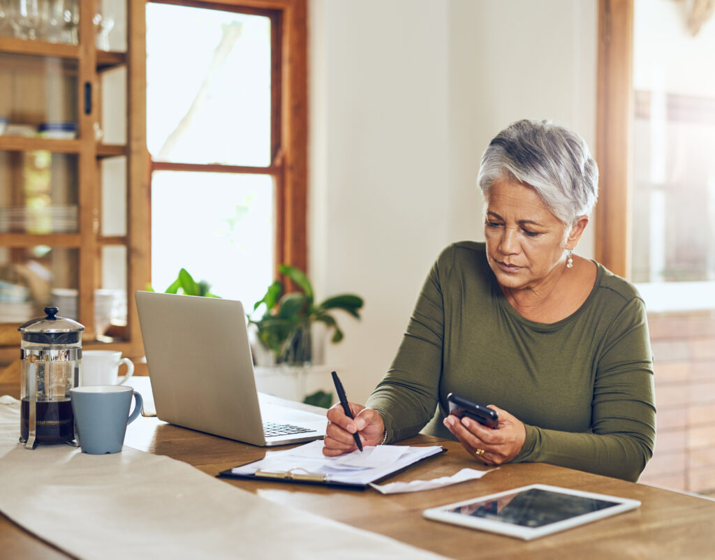 Woman writing and looking at her phone